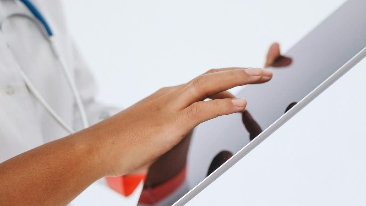 A healthcare professional who looks at the health data of a tablet.