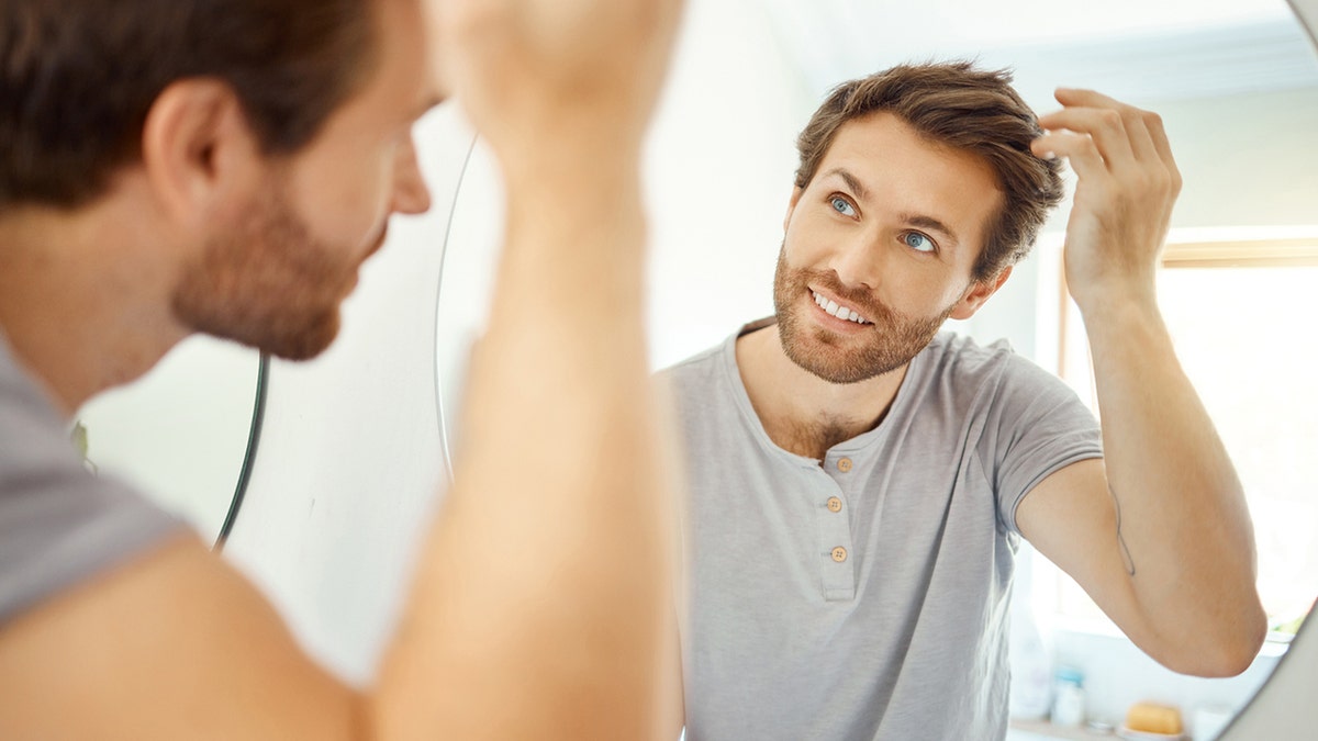 Man who combes his hair in a bathroom at home